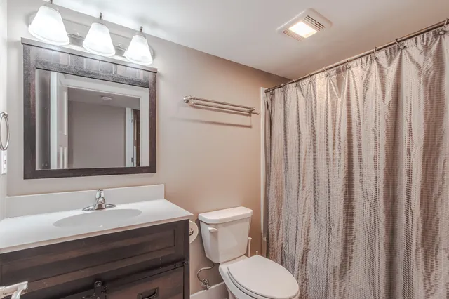 a bathroom with a granite countertop sink vanity mirror and toilet