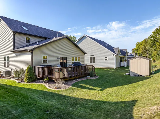 a view of a white house in front of a big yard with potted plants