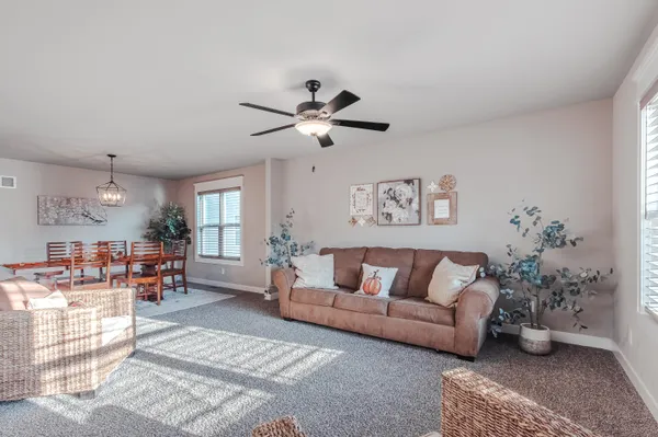 a living room with furniture kitchen view and a chandelier
