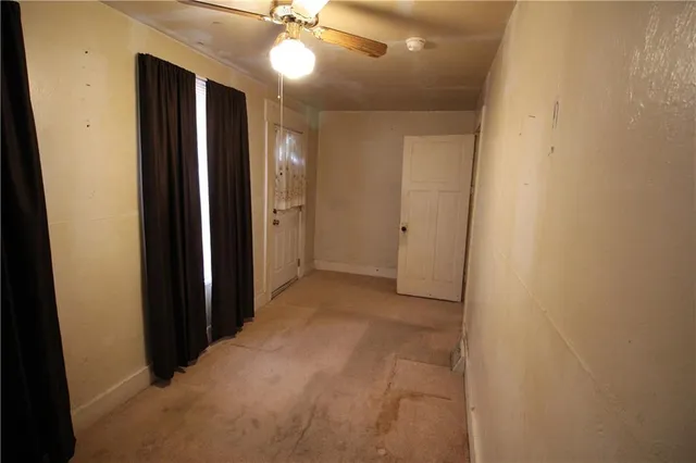 an empty room with a chandelier fan and a bathroom