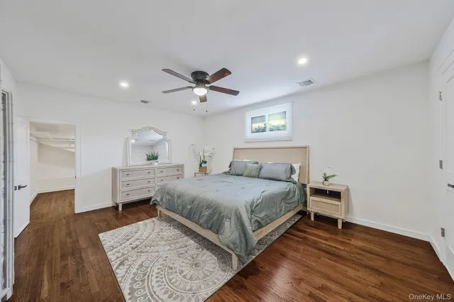 a bedroom with a bed a chandelier with dresser and mirror