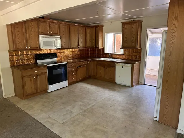 a kitchen with granite countertop a refrigerator stove top oven and sink