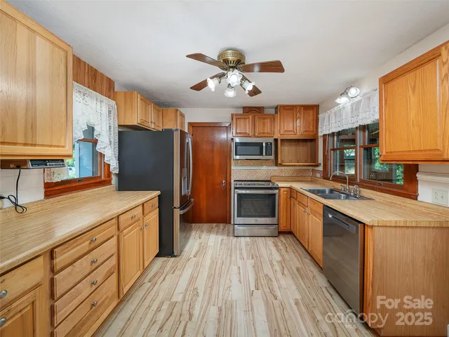 a kitchen with stainless steel appliances granite countertop a refrigerator a sink dishwasher a stove with wooden cabinets and floor