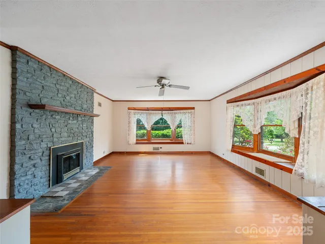 a view of an empty room with a fireplace window and wooden floor
