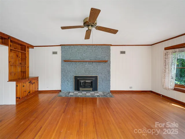 a view of empty room with wooden floor and fan
