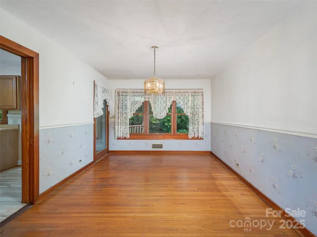 a view of an empty room with window wooden floor and chandelier