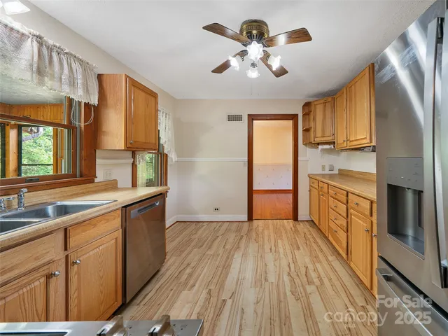 a kitchen with stainless steel appliances granite countertop a refrigerator a sink dishwasher a stove and white countertops with wooden floor