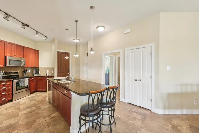 a kitchen with granite countertop a stove a sink a dining table and chairs