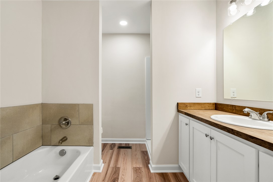 131 Lockaby Road Pelzer, SC 29669 - Photo 26 of 50 This bright bathroom features a vanity with a white basin and a bathtub with tiled surround.