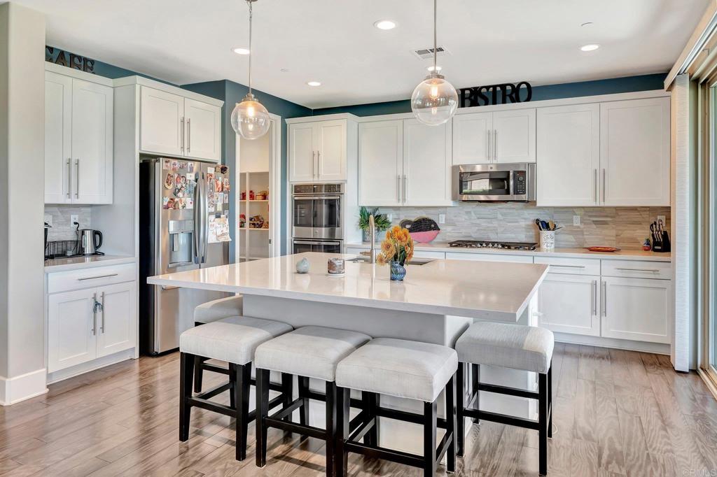 35822 Blue Breton Drive Fallbrook, CA 92028 - Photo 13 of 47 a kitchen with kitchen island granite countertop a refrigerator stove microwave and white cabinets