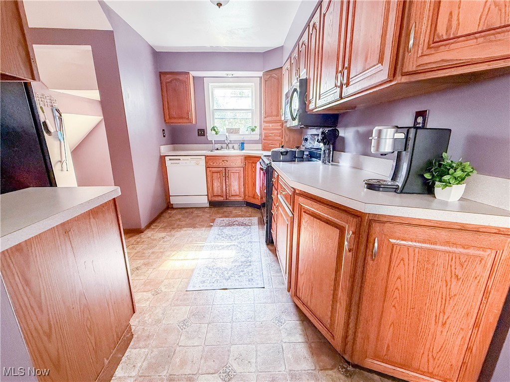 4672 Liberty Road South Euclid, OH 44121 - Photo 8 of 23 Kitchen featuring stove, light countertops, dishwasher, freestanding refrigerator, and brown cabinets