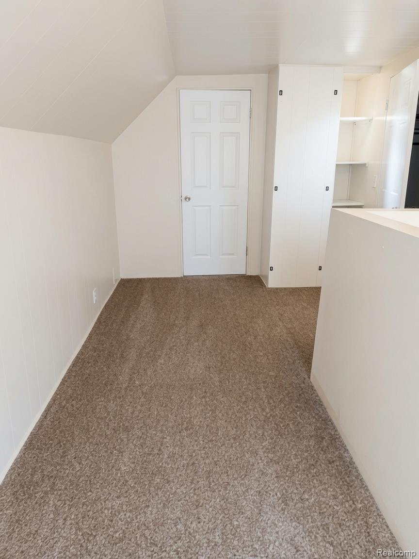 16069 Liberal Street Detroit, MI 48205 - Photo 3 of 9 Carpeted interior space featuring an angled ceiling, white six-panel door, and built-in shelving