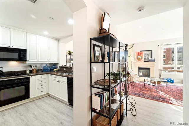 a kitchen with stainless steel appliances granite countertop a stove top oven a sink a dining table and chairs with wooden floor