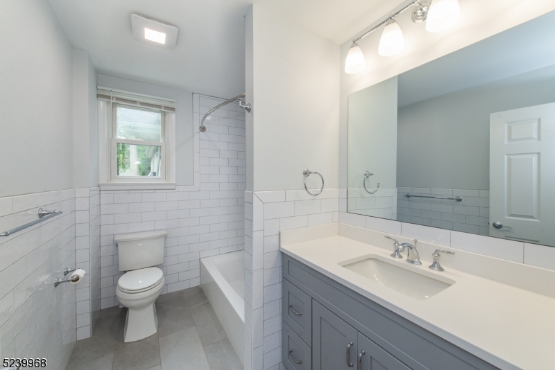 68 Orchard Street, Unit 1 Summit, NJ 07901 - Photo 17 of 23 a bathroom with a granite countertop toilet a sink and a mirror