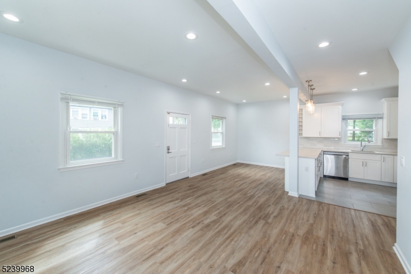 68 Orchard Street, Unit 1 Summit, NJ 07901 - Photo 3 of 23 a view of a kitchen and an empty room with wooden floor and a window