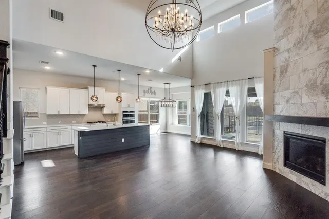 a large kitchen with stainless steel appliances granite countertop a stove a sink dishwasher a refrigerator white cabinets and wooden floor