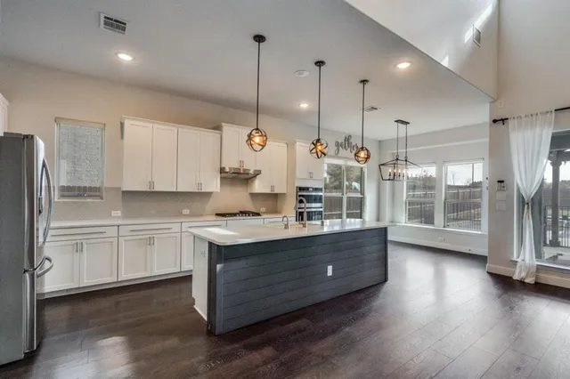 a kitchen with stainless steel appliances granite countertop a sink a stove and a wooden floor