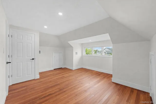 a view of an empty room with wooden floor and window