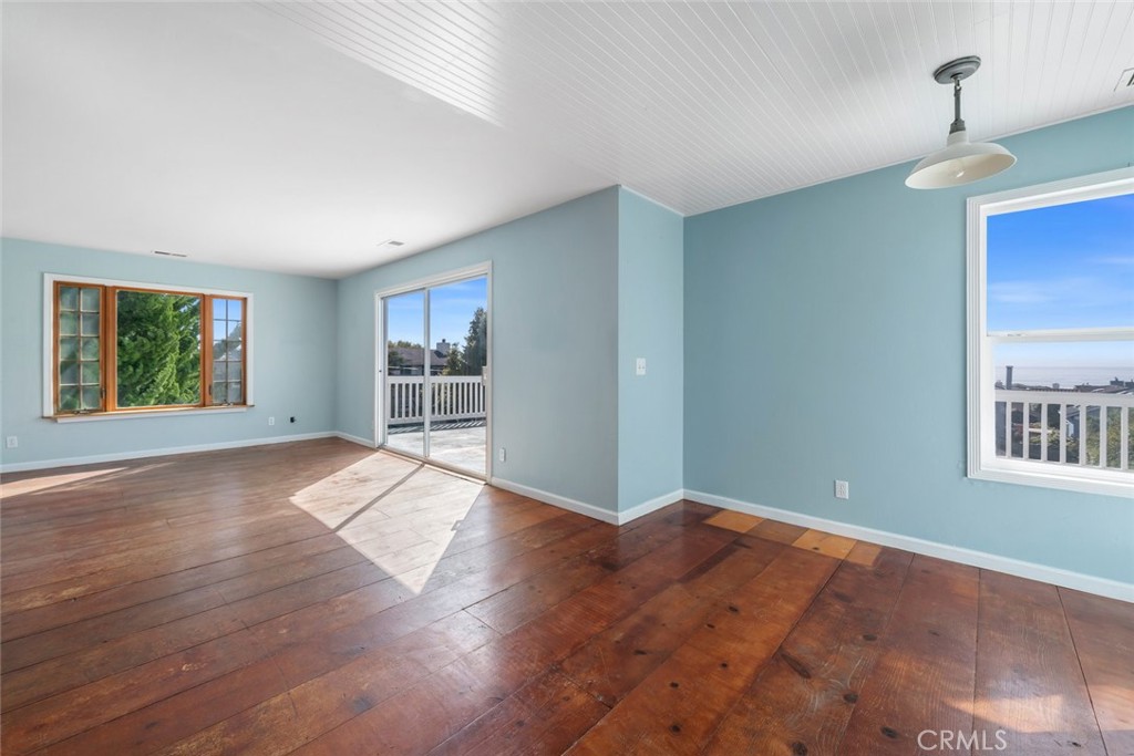 379 Harvey Street Cambria, CA 93428 - Photo 17 of 52 an empty room with wooden floor and windows