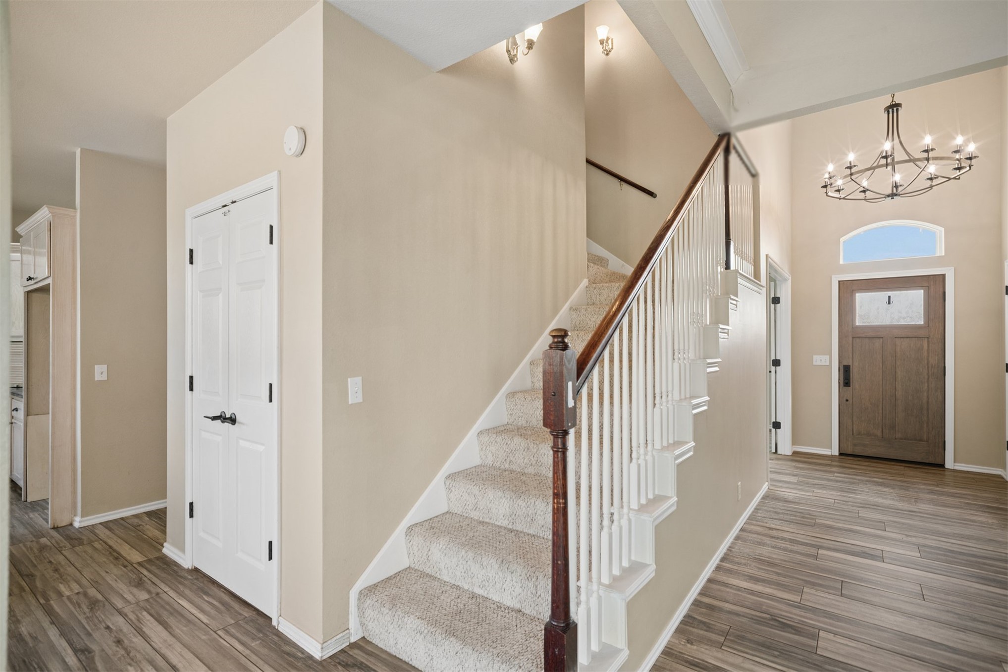 175 Alt 75 Mounds, OK 74047 - Photo 19 of 41 Two-story entryway featuring wood-finish flooring, a carpeted staircase with a wood handrail, an arched transom window, and a chandelier