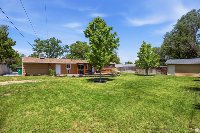 6889 South Village Road Salt Lake City, UT 84121 - Photo 35 of 44 Expansive lawn area with mature trees and a detached shed