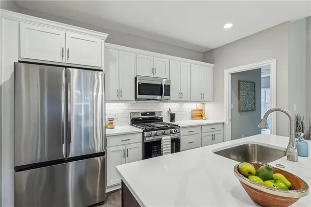 a kitchen with stainless steel appliances granite countertop a refrigerator a stove a sink dishwasher and a refrigerator with wooden floor