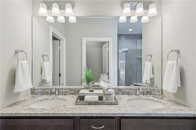 a bathroom with a granite countertop double vanity sink and a mirror