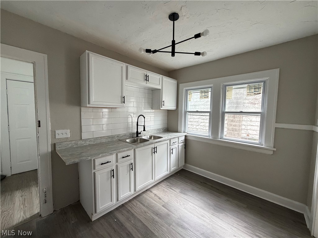 15317 Shiloh Road Cleveland, OH 44110 - Photo 27 of 29 Kitchen featuring white cabinetry, subway tile backsplash, dual basin stainless steel sink, and wood-finish flooring