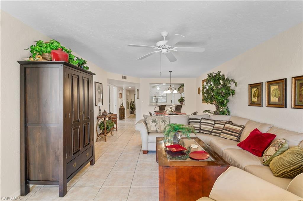 776 Landover Circle, Unit 104 Naples, FL 34104 - Photo 13 of 25 a living room with furniture flowerpot and a chandelier