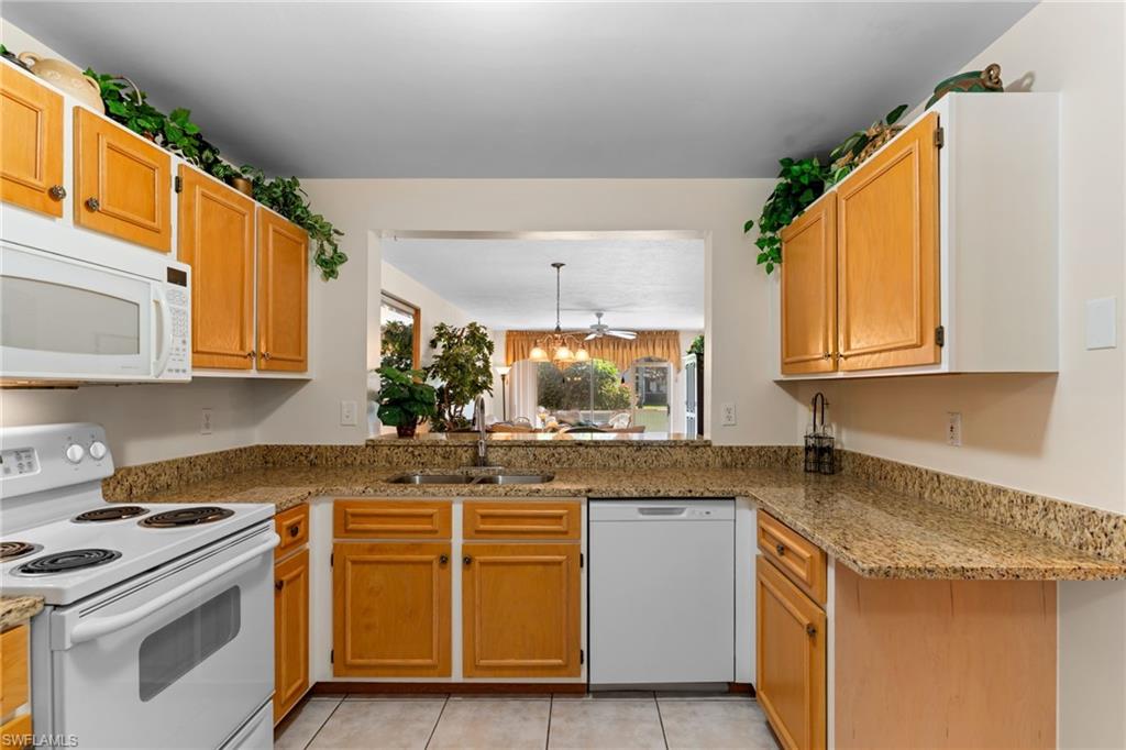 776 Landover Circle, Unit 104 Naples, FL 34104 - Photo 3 of 25 a kitchen with granite countertop a sink a stove and cabinets