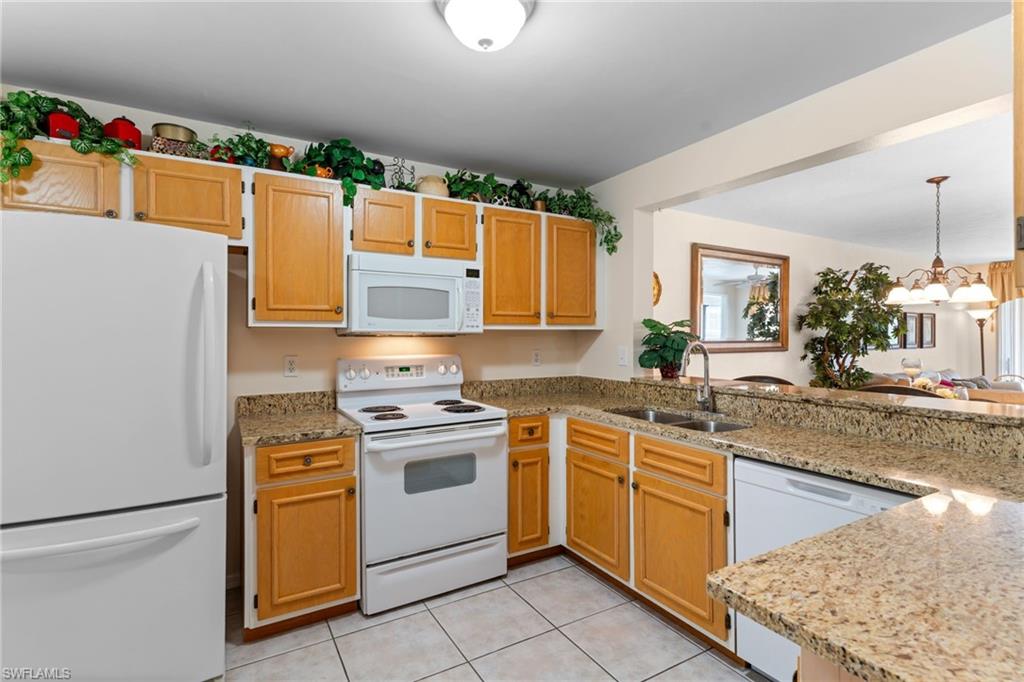 776 Landover Circle, Unit 104 Naples, FL 34104 - Photo 4 of 25 a kitchen with stainless steel appliances granite countertop a sink stove and refrigerator