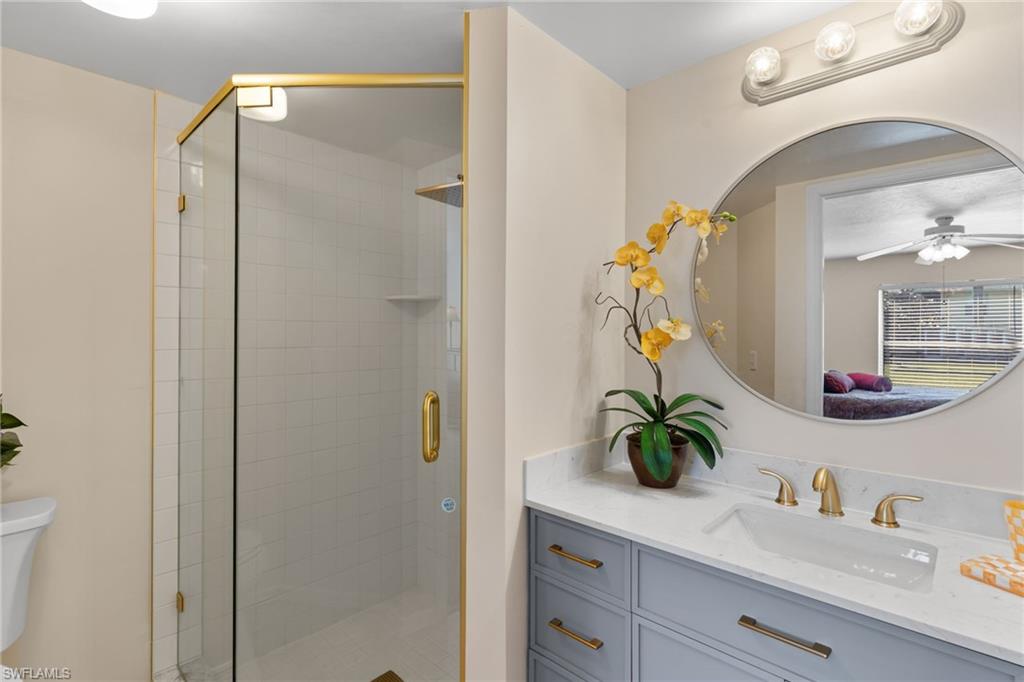 776 Landover Circle, Unit 104 Naples, FL 34104 - Photo 6 of 25 a bathroom with a granite countertop sink a potted plant and a shower