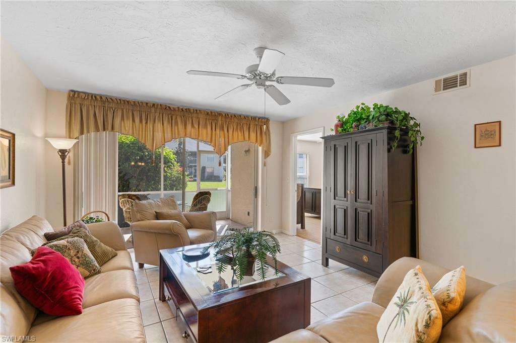 776 Landover Circle, Unit 104 Naples, FL 34104 - Photo 10 of 25 a living room with furniture ceiling fan and a large window