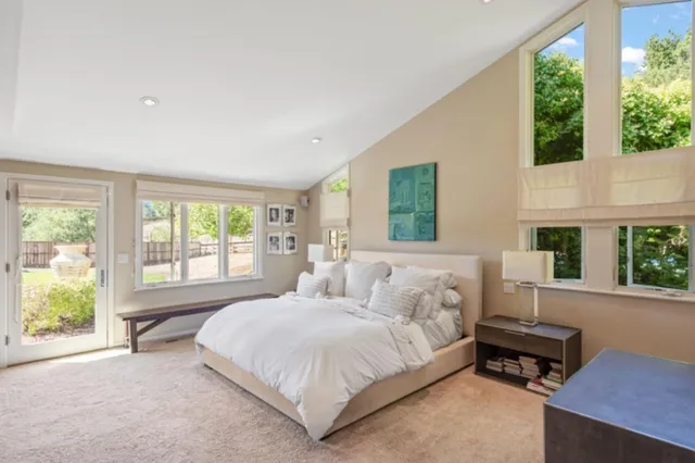 a spacious bedroom with a bed a table and windows