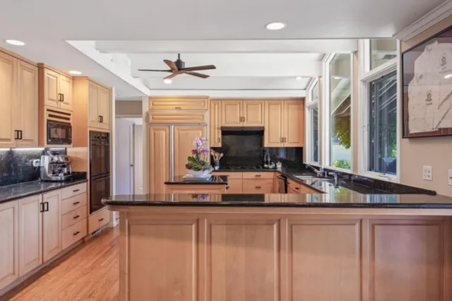 a kitchen with stainless steel appliances granite countertop a sink and a granite counter tops with wooden floors