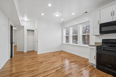 a view of an empty room with a window and a kitchen