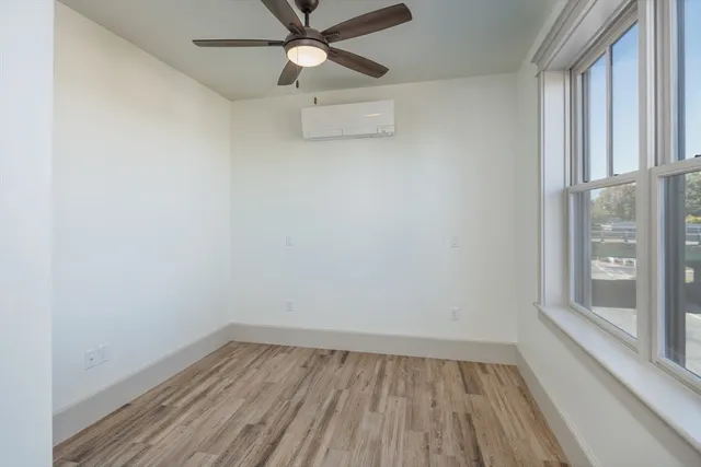 a view of an empty room with wooden floor and a window