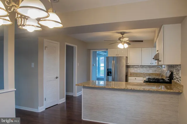 a view of a kitchen island a chandelier and wooden floor