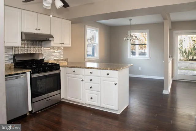 a kitchen with stainless steel appliances a white stove top oven cabinets and a wooden floor