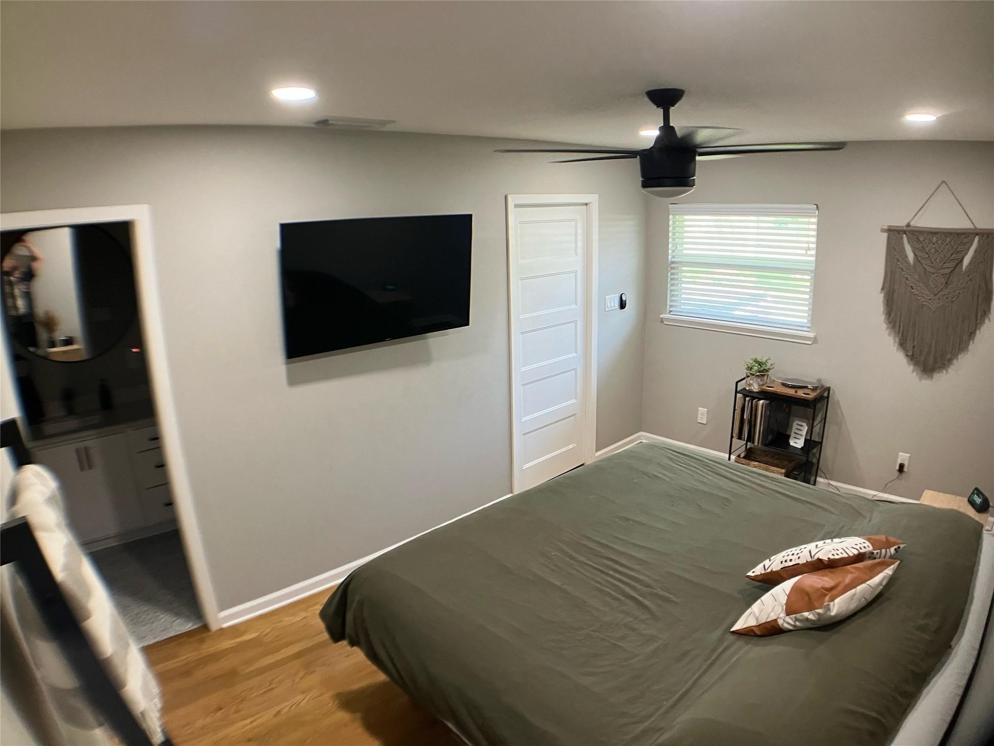 3027 Guese Road Houston, TX 77018 - Photo 12 of 22 Comfortable bedroom features warm flooring, natural light, and a mounted TV setup for convenience.
