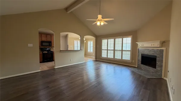 a view of an empty room with window and wooden floor