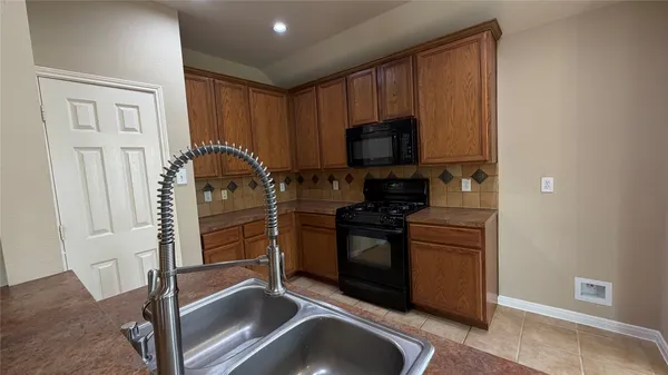 a kitchen with granite countertop a refrigerator and a stove top oven