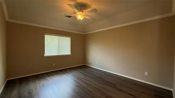 an empty room with wooden floor fan and windows