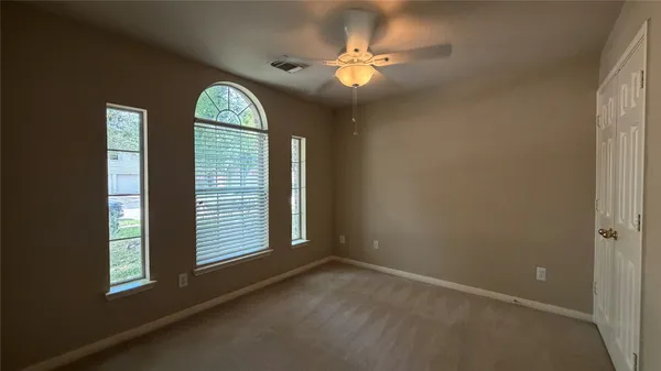 an empty room with windows and chandelier fan