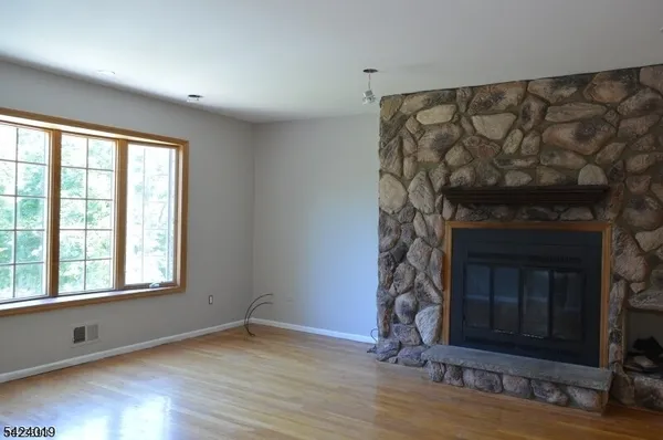 a view of an empty room with wooden floor and a fireplace