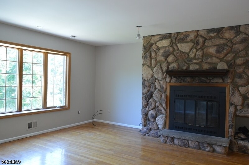 89 Forsythia Lane, Unit A Paramus, NJ 07652 - Photo 4 of 12 a view of an empty room with wooden floor and a fireplace