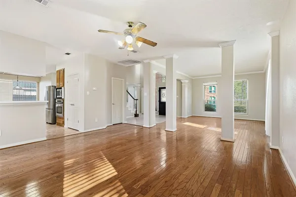 a view of an empty room with wooden floor and a kitchen
