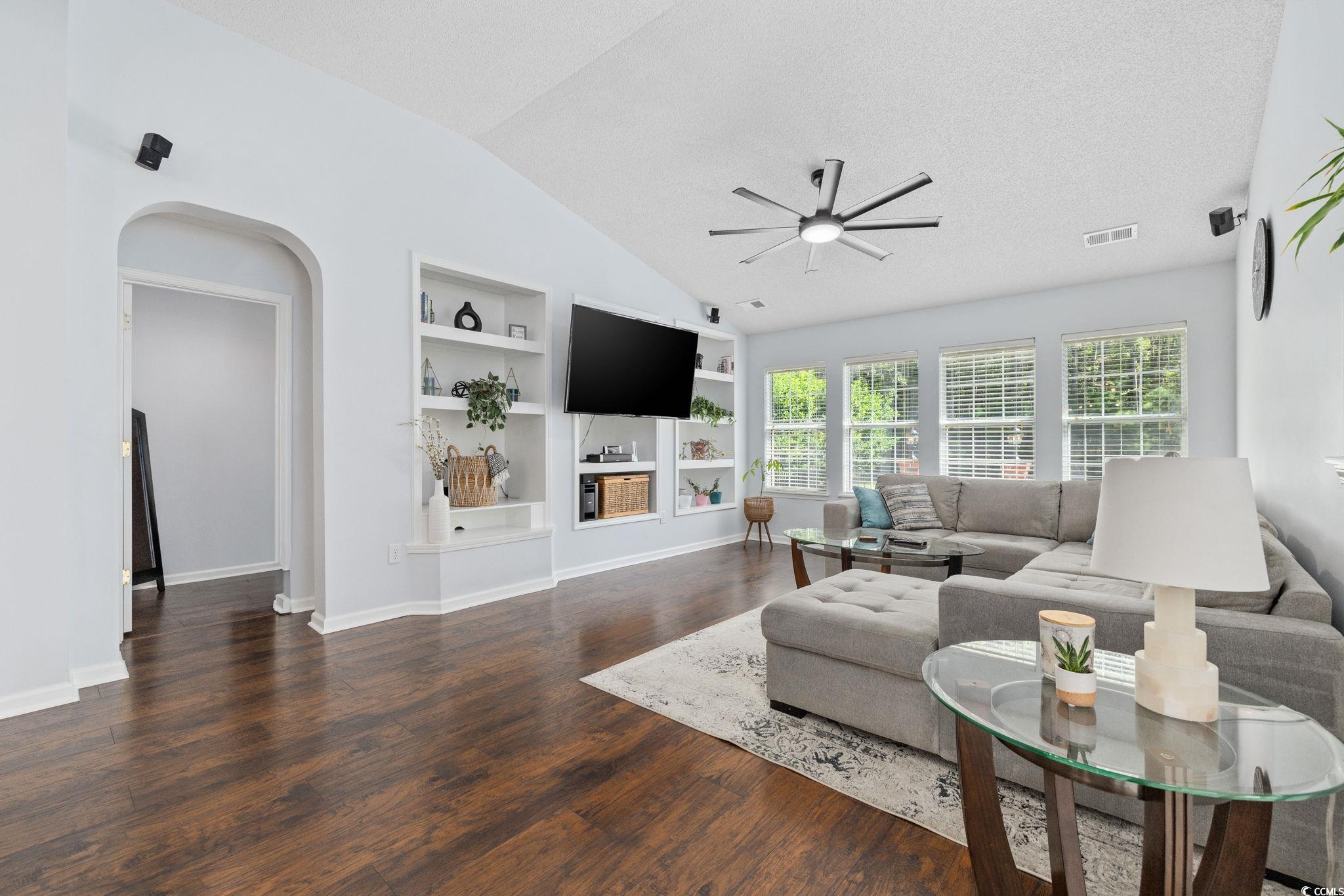 1409 Lanterns Rest Road Myrtle Beach, SC 29579 - Photo 16 of 40 Living area with built in features, arched walkways, lofted ceiling, dark wood-style flooring, and a ceiling fan