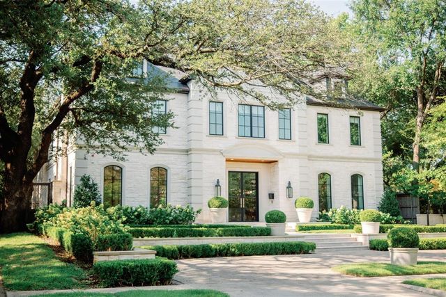 a view of a white house with a tree and plants