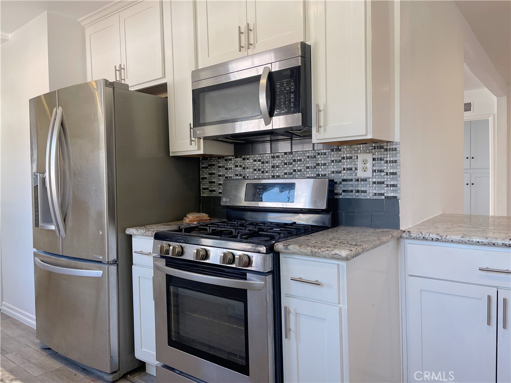 15100 Dunton Drive Whittier, CA 90604 - Photo 8 of 17 a kitchen with stainless steel appliances granite countertop a stove microwave and refrigerator
